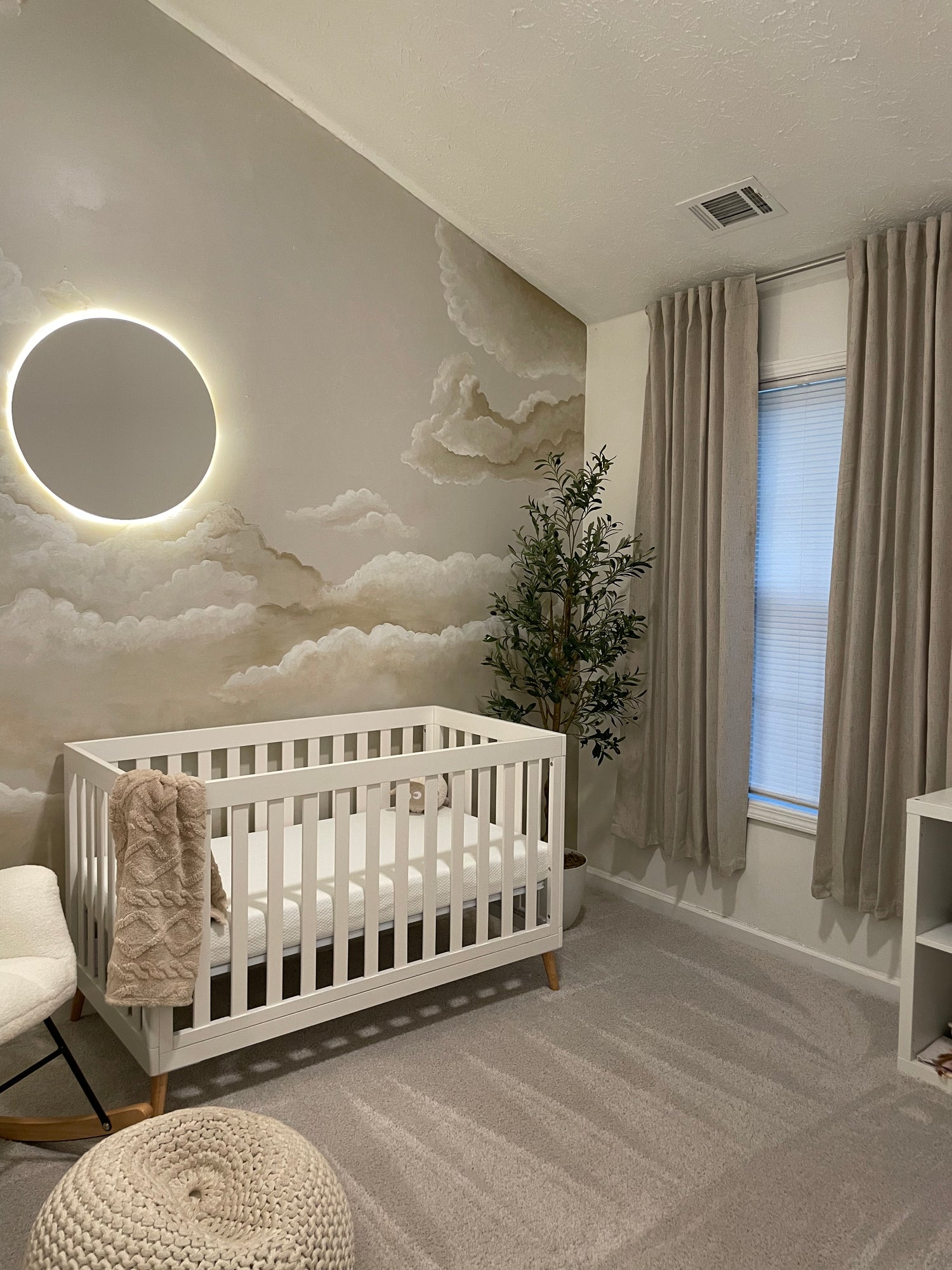 a cloud mural in a baby nursery in nude and cream tones. Modern nursery home decor